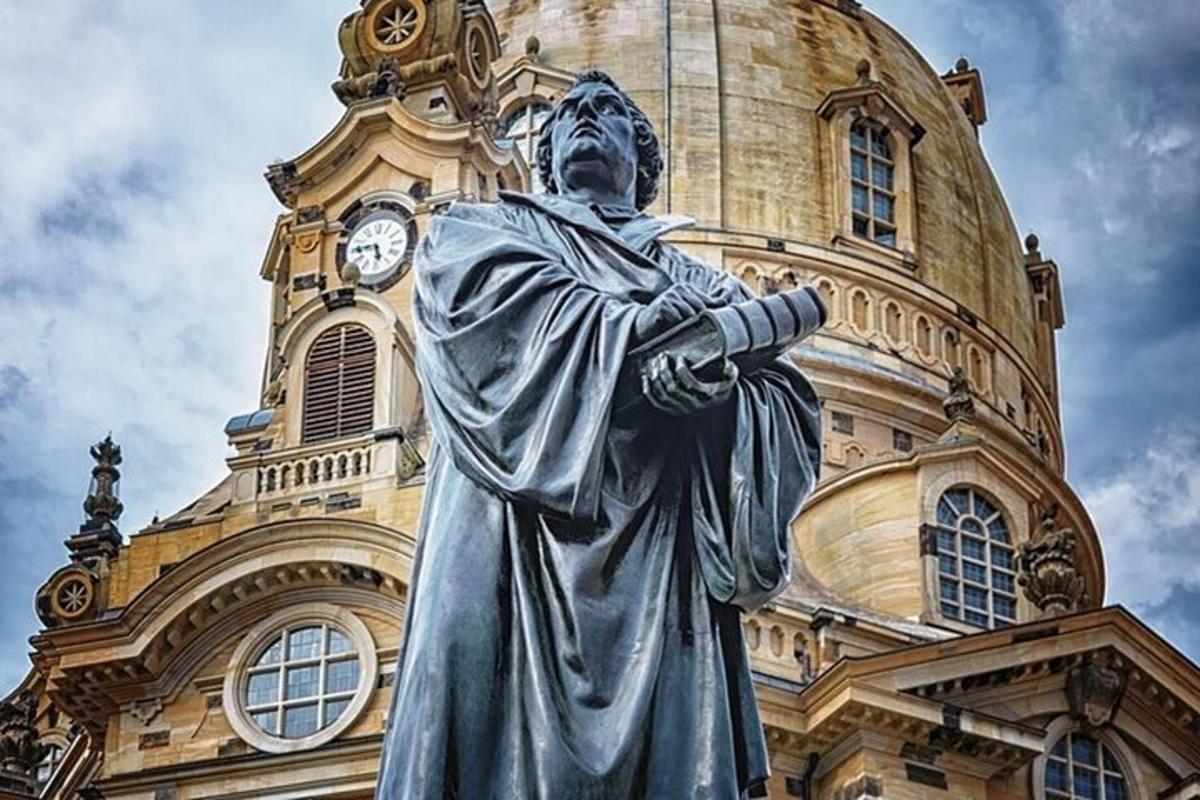 uma estátua em frente a um prédio com uma torre de relógio