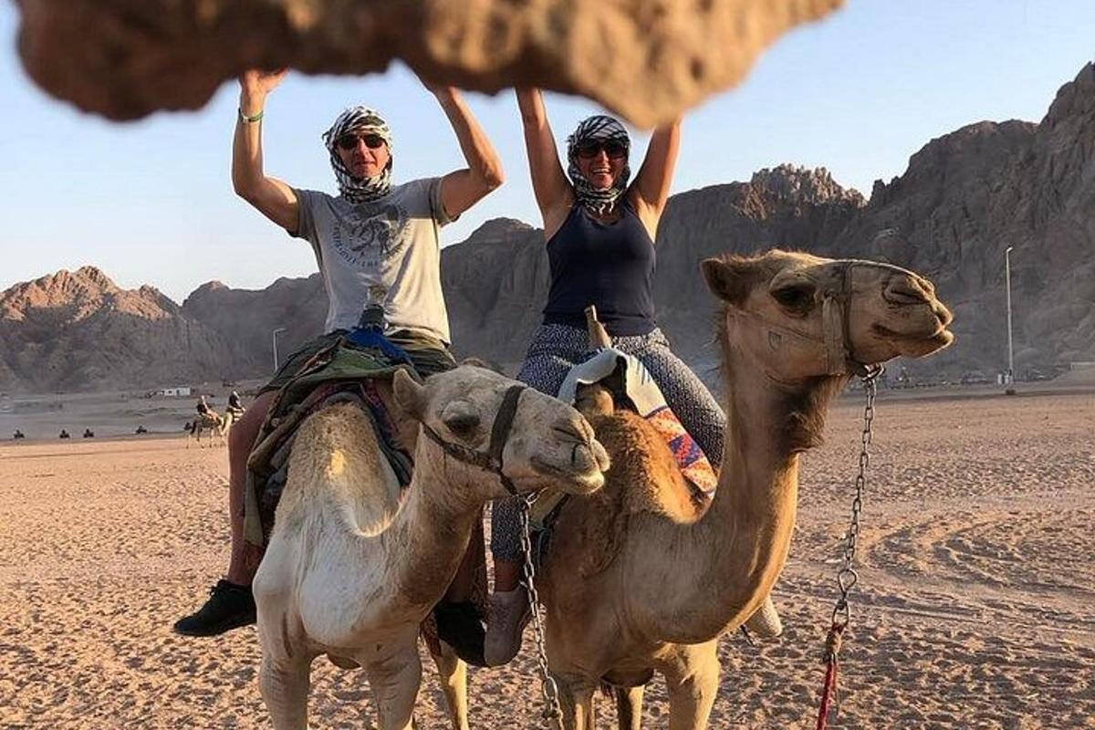 two people riding on the backs of camels in the desert