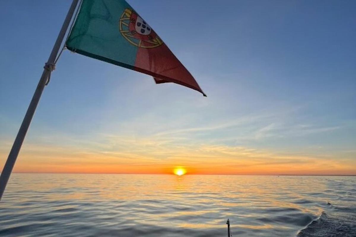 a flag on a boat in the water with a sunset