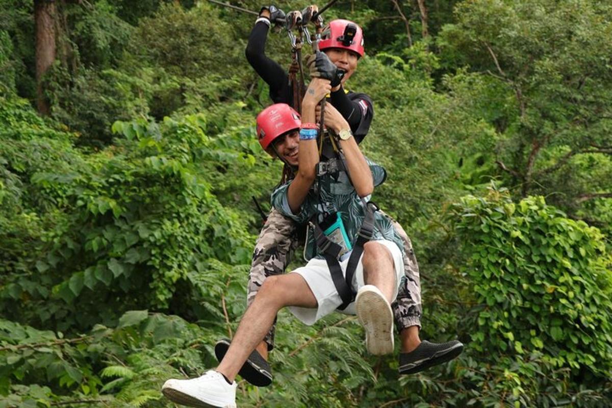 two men are on a zip line in the jungle