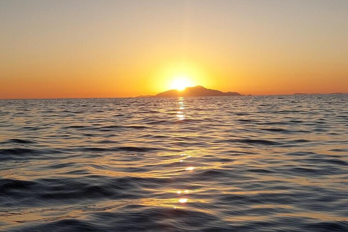Západ slunce nad oceánem s horou v pozadí