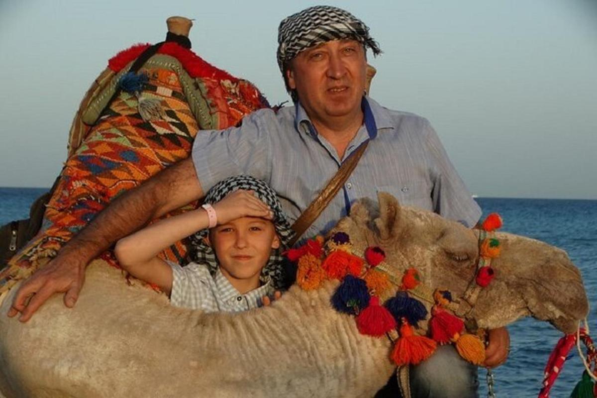 чоловік і дитина сидять на спині верблюда
