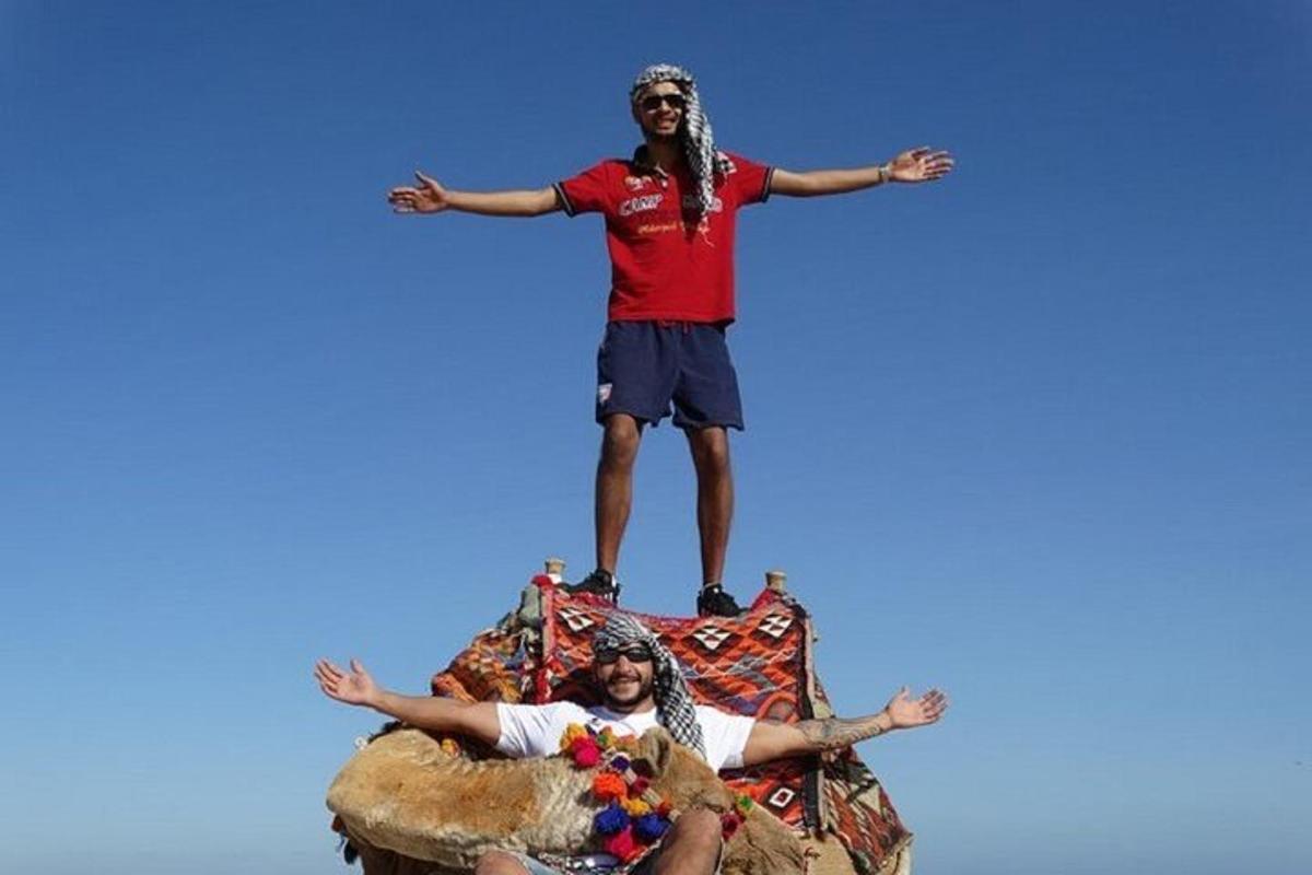 Dos hombres de pie sobre el lomo de un elefante