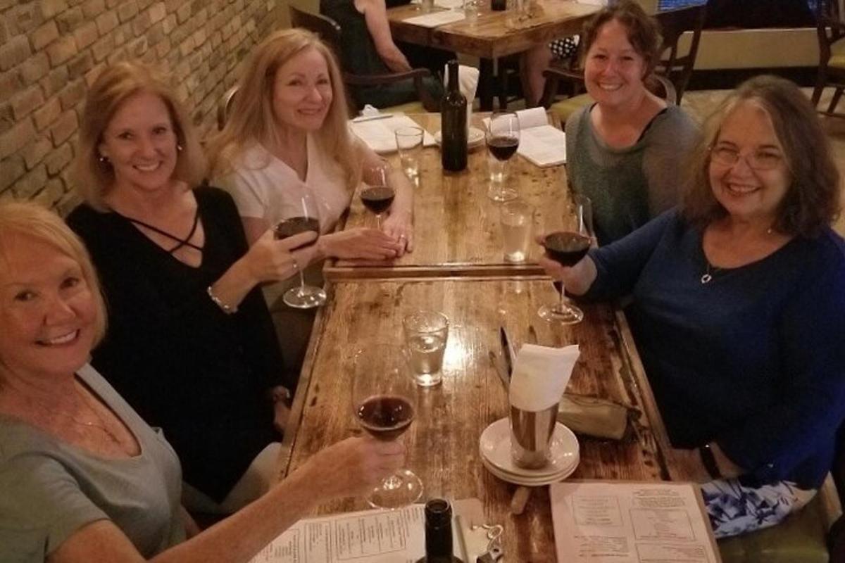 a group of women sitting around a table with wine glasses