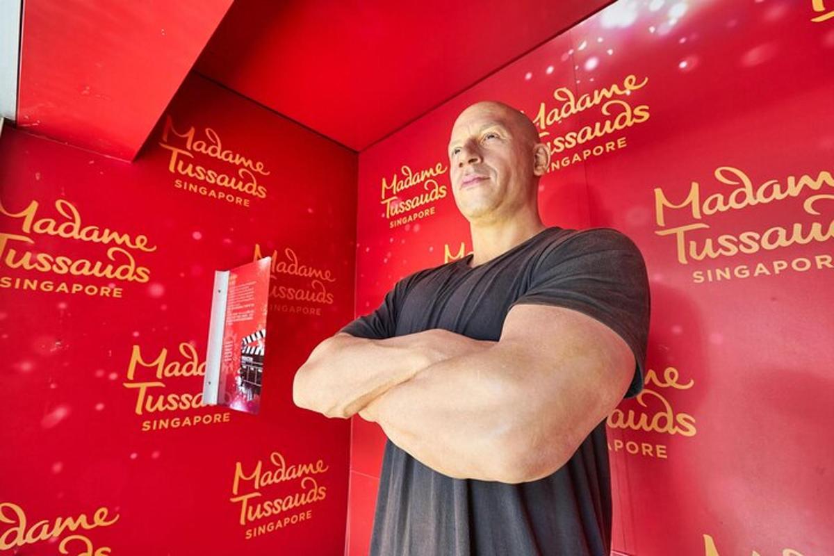 a man standing in front of a red wall with his arms crossed