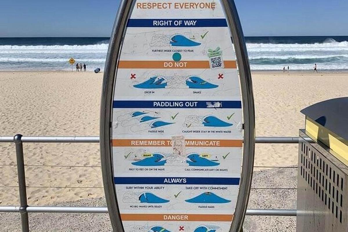 een bord voor een strand met een surfplank