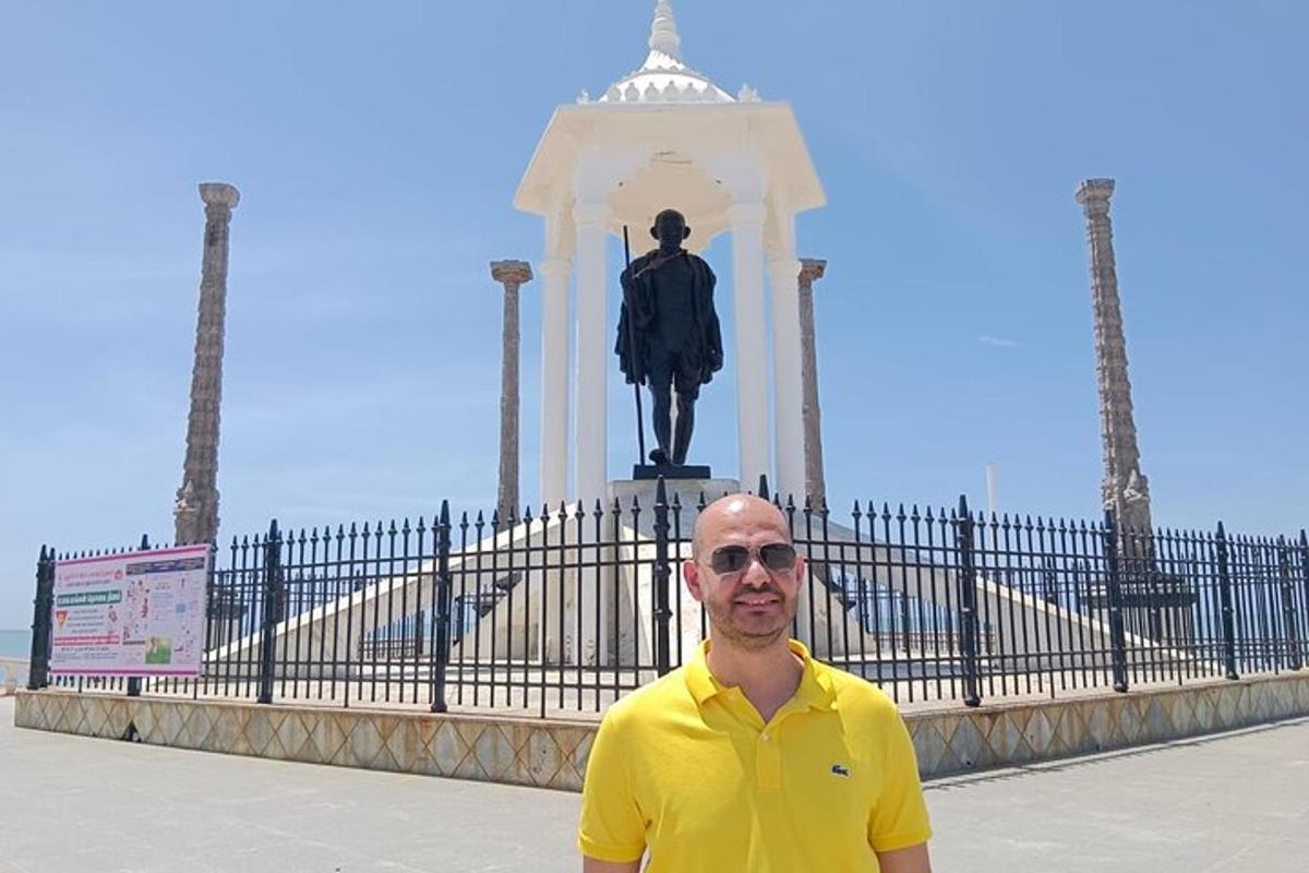 a man in a yellow shirt standing in front of a statue