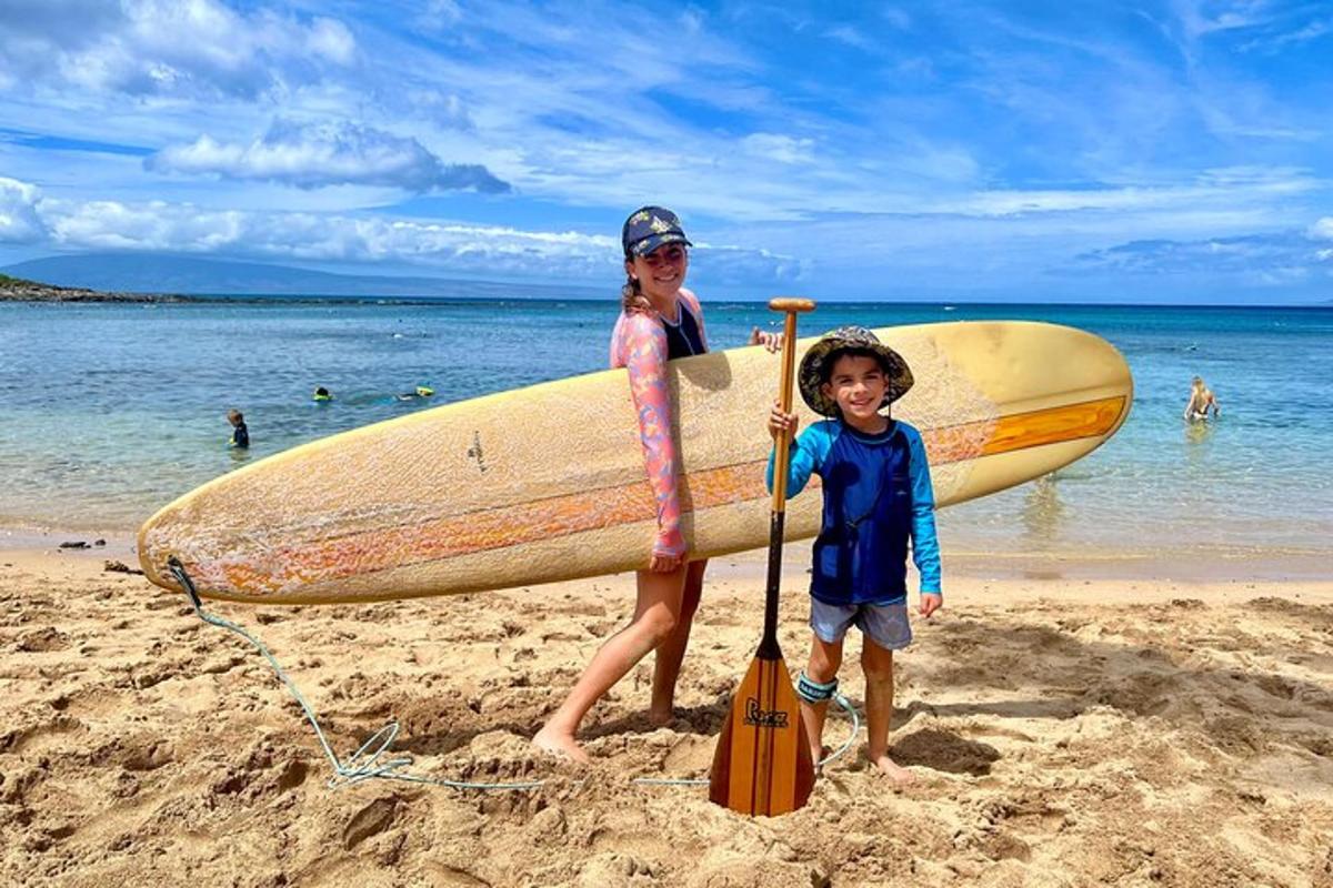 a woman and a child holding a surfboard on the beach
