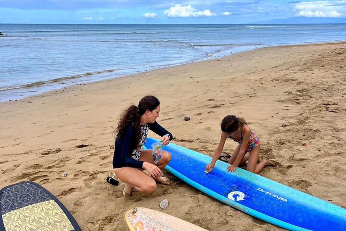 two girls playing on the beach with a surfboard