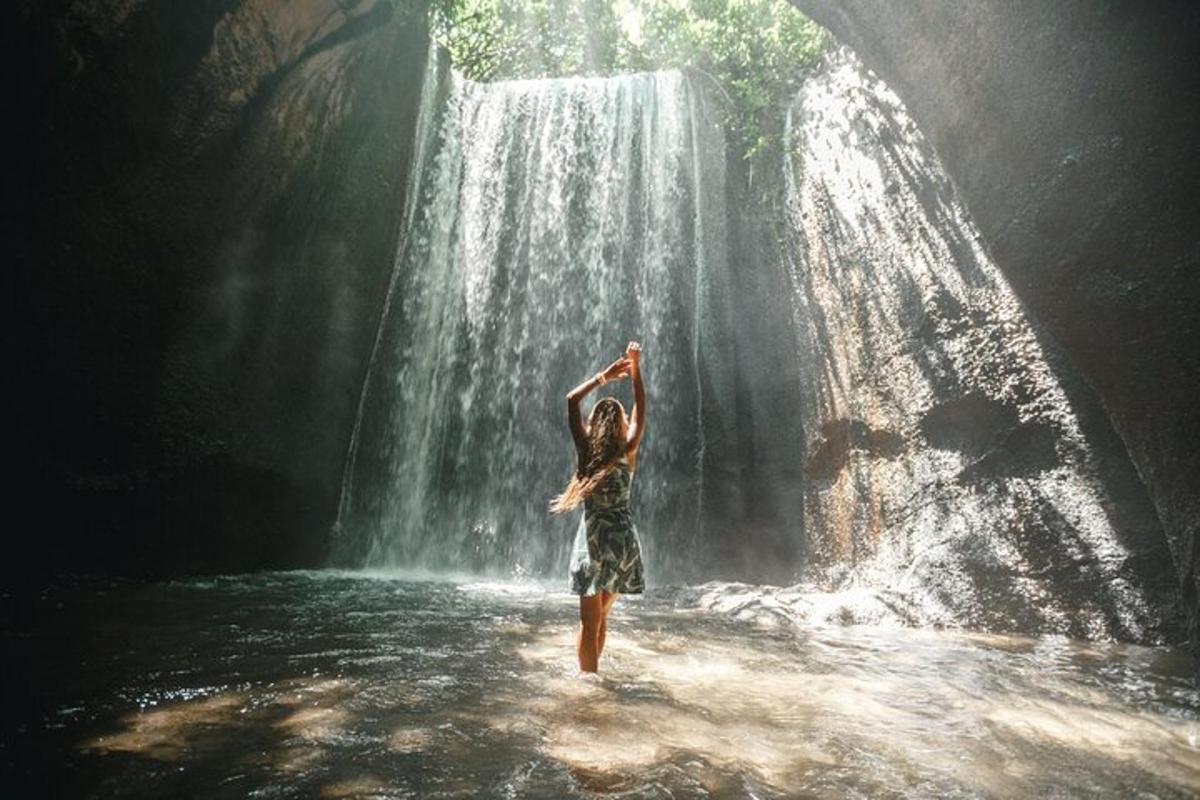 uma mulher parada na água em frente a uma cachoeira