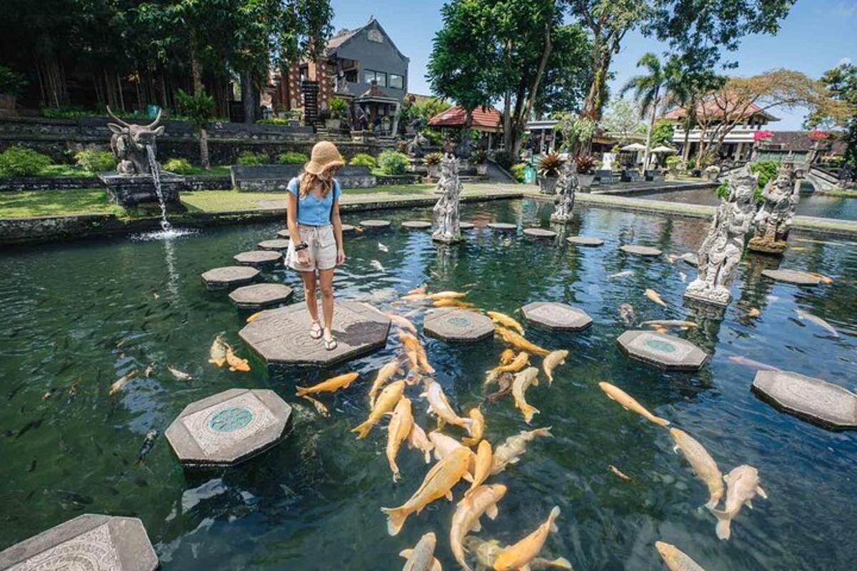 seorang wanita berdiri di atas pelantar di kolam dengan ikan emas