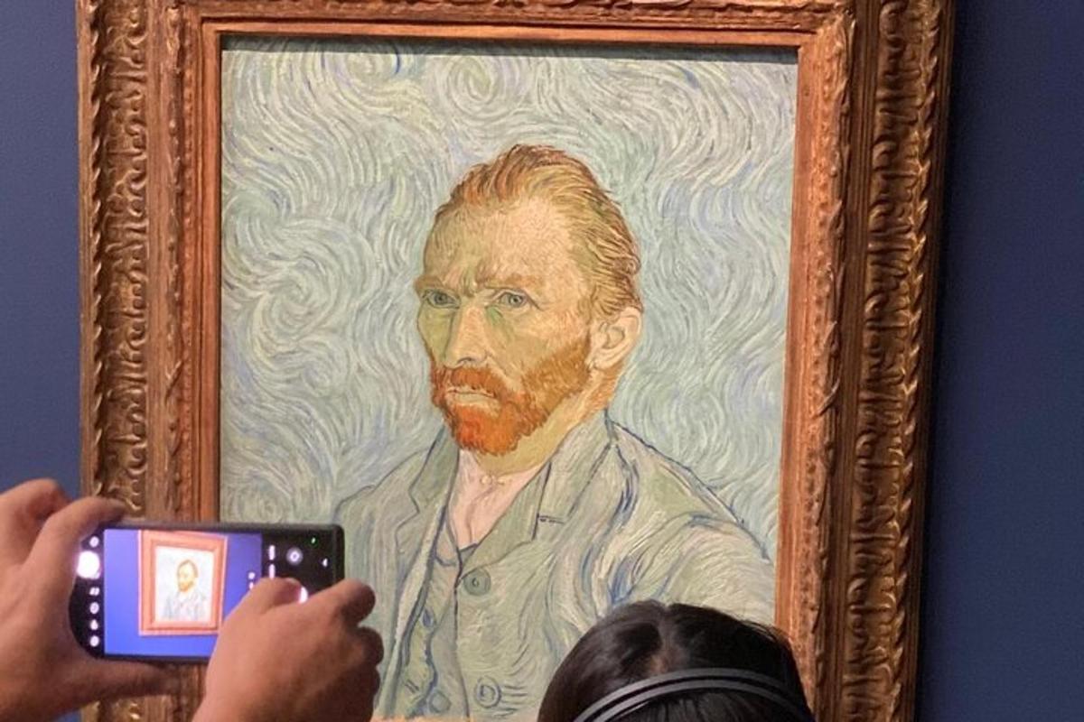 a person taking a picture of a painting of an older man