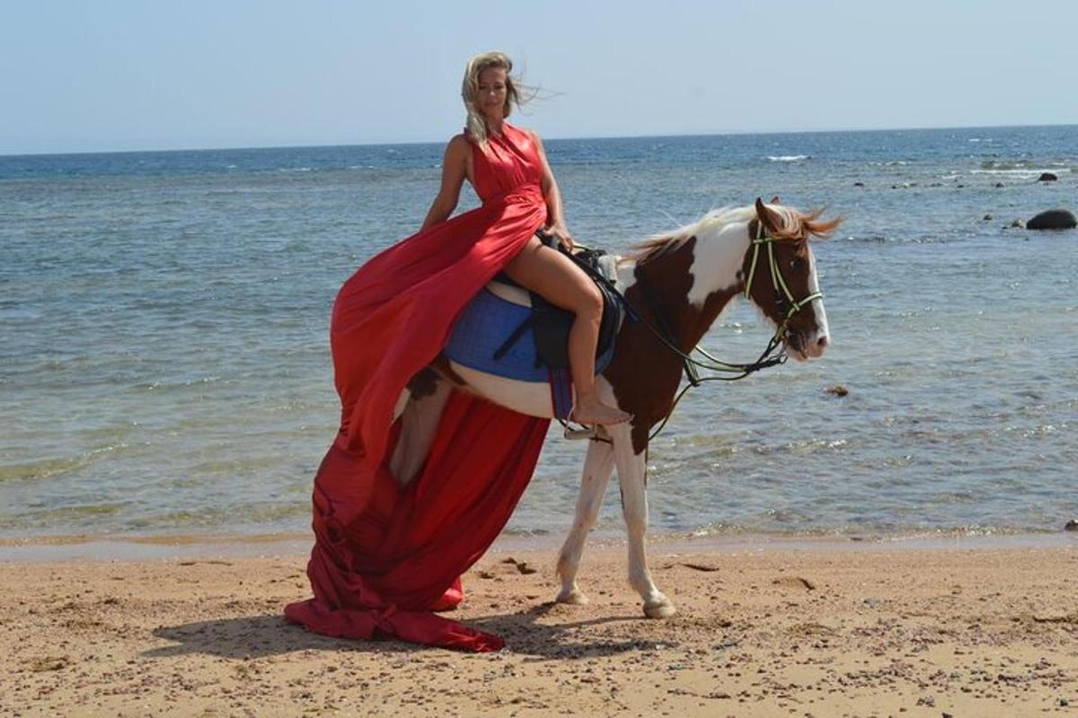 žena v šatech jedoucí na koni na pláži