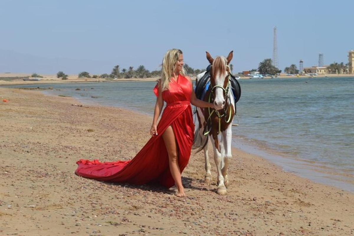 una donna in un vestito rosso con un cavallo sulla spiaggia