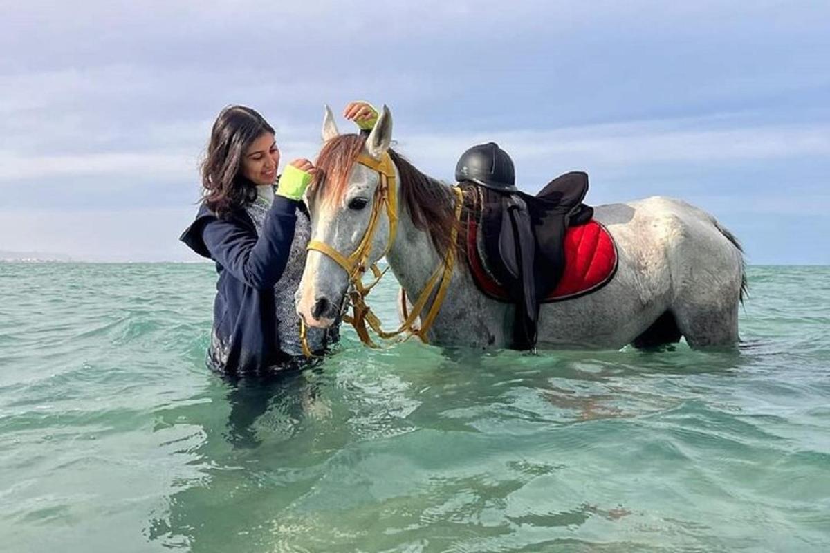 žena stojící vedle koně v oceánu