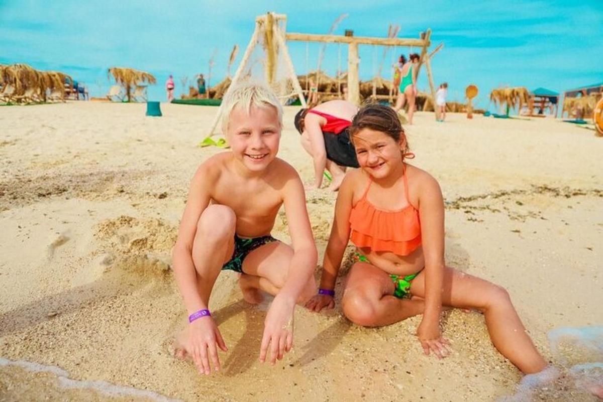 two young children sitting in the sand on the beach