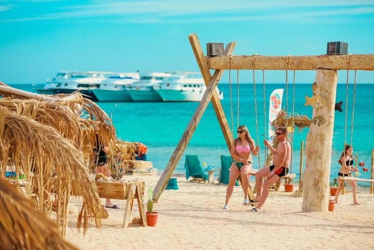 two people sitting on a swing on the beach