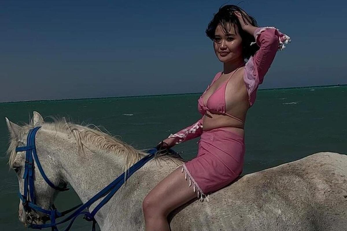 una donna in un vestito rosa a cavallo nell'oceano
