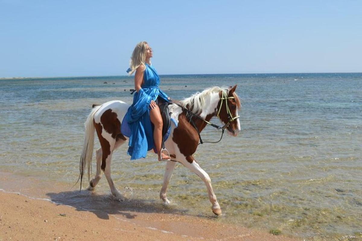 egy kék ruhás nő lovagol a tengerparton