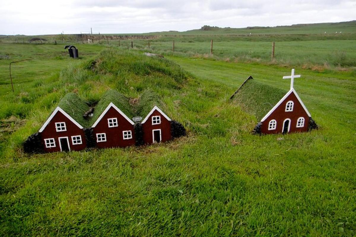hópur húsa í graslendi með krossi