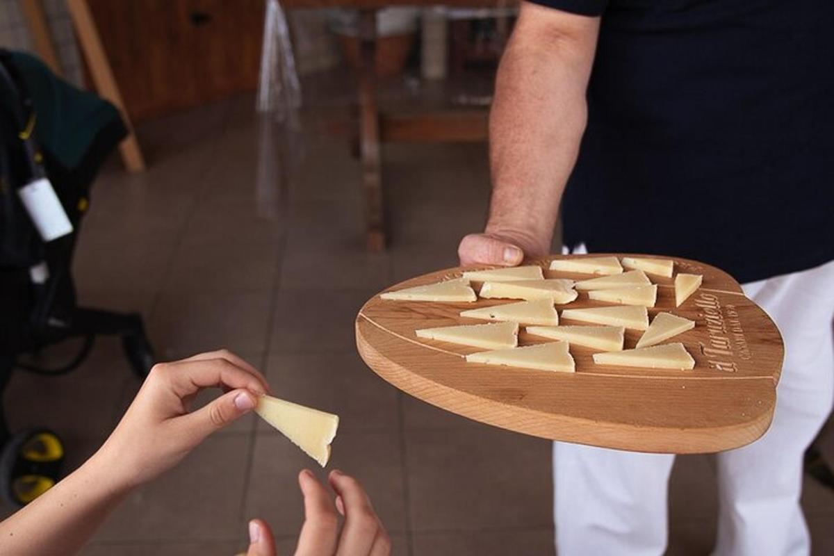 uma pessoa segurando um prato de queijo em uma tábua de corte