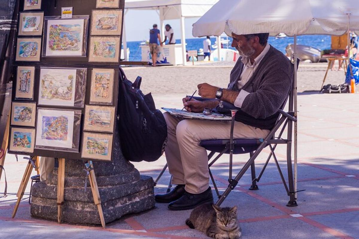 a man sitting in a chair under an umbrella next to a cat