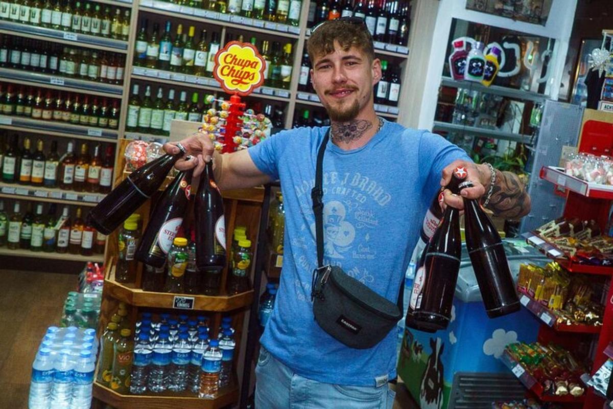 un home dret en una botiga amb un munt d'ampolles a la mà