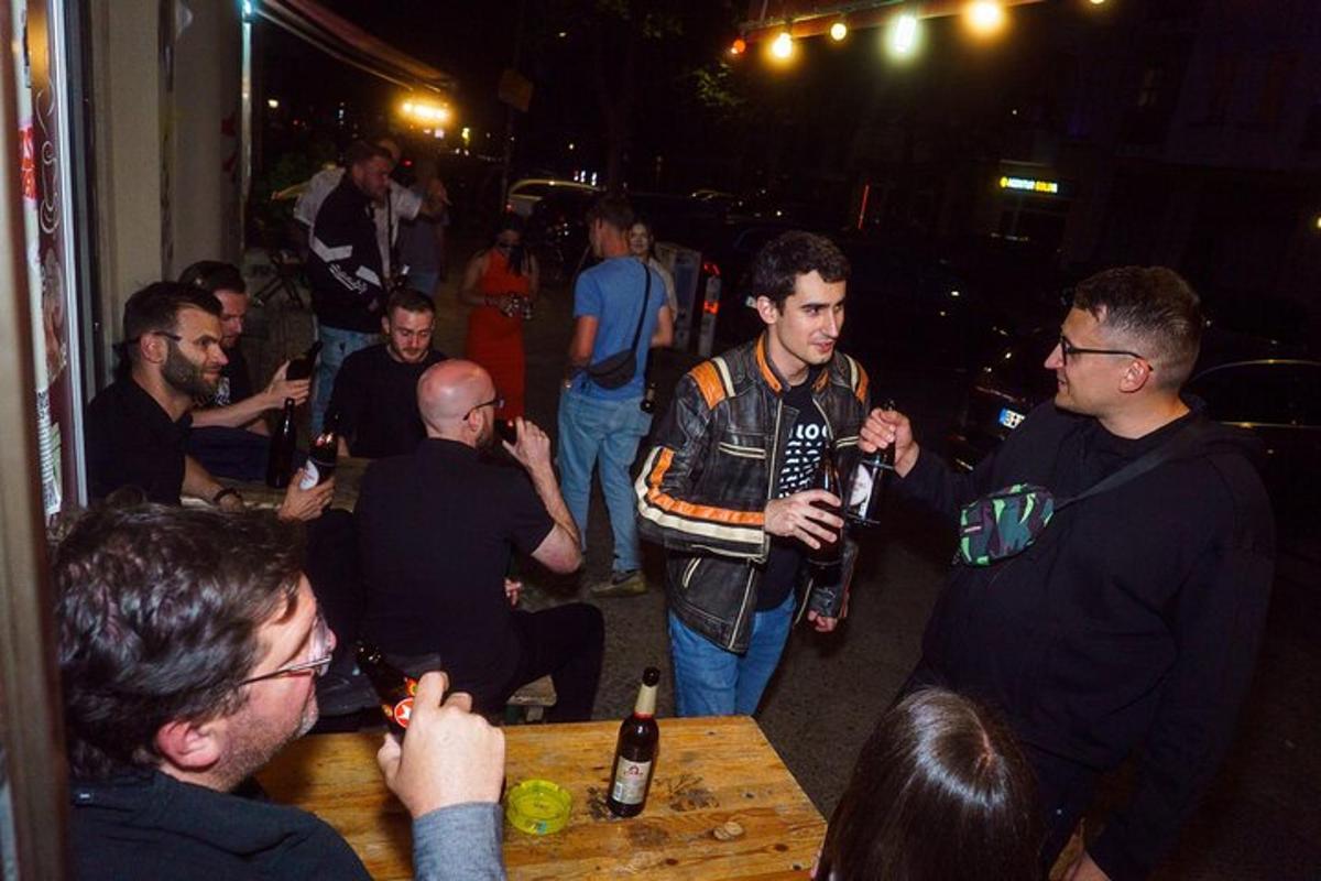 een groep mensen die rond een tafel staan met flessen bier