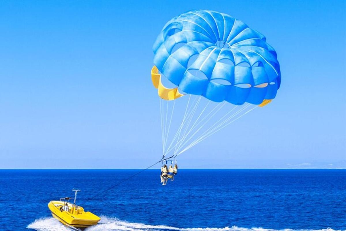 a blue parachute flying over a yellow boat in the ocean
