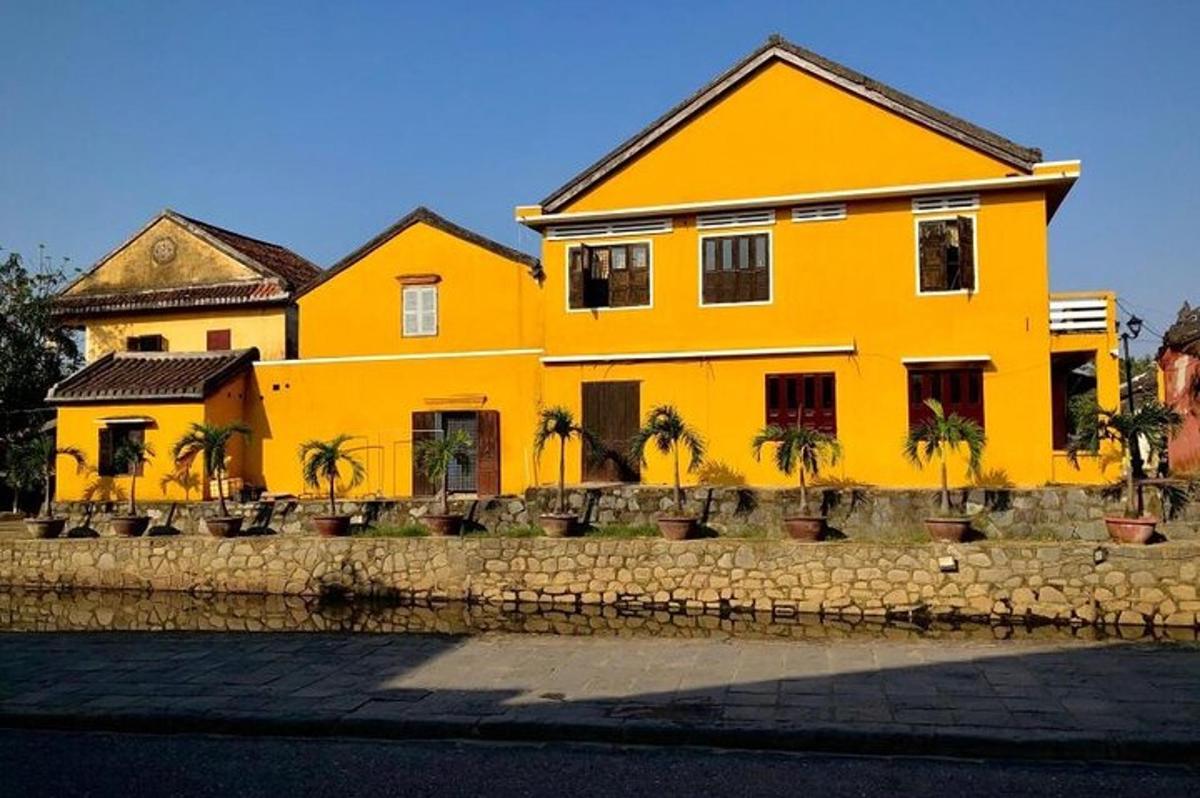 una casa gialla con palme di fronte
