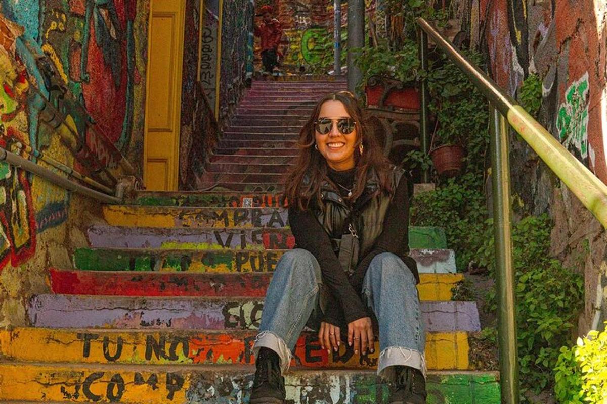 Una mujer sentada en unas escaleras frente a un cuadro.