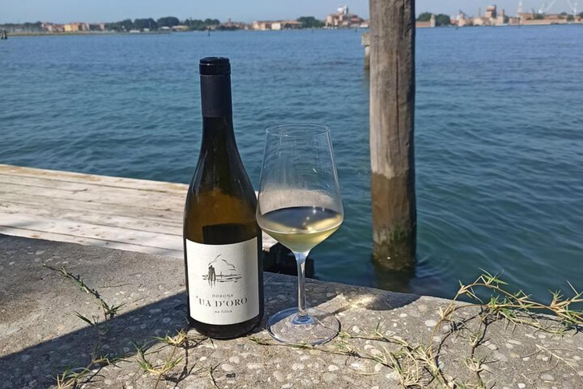 una botella de vino blanco junto a una copa de vino