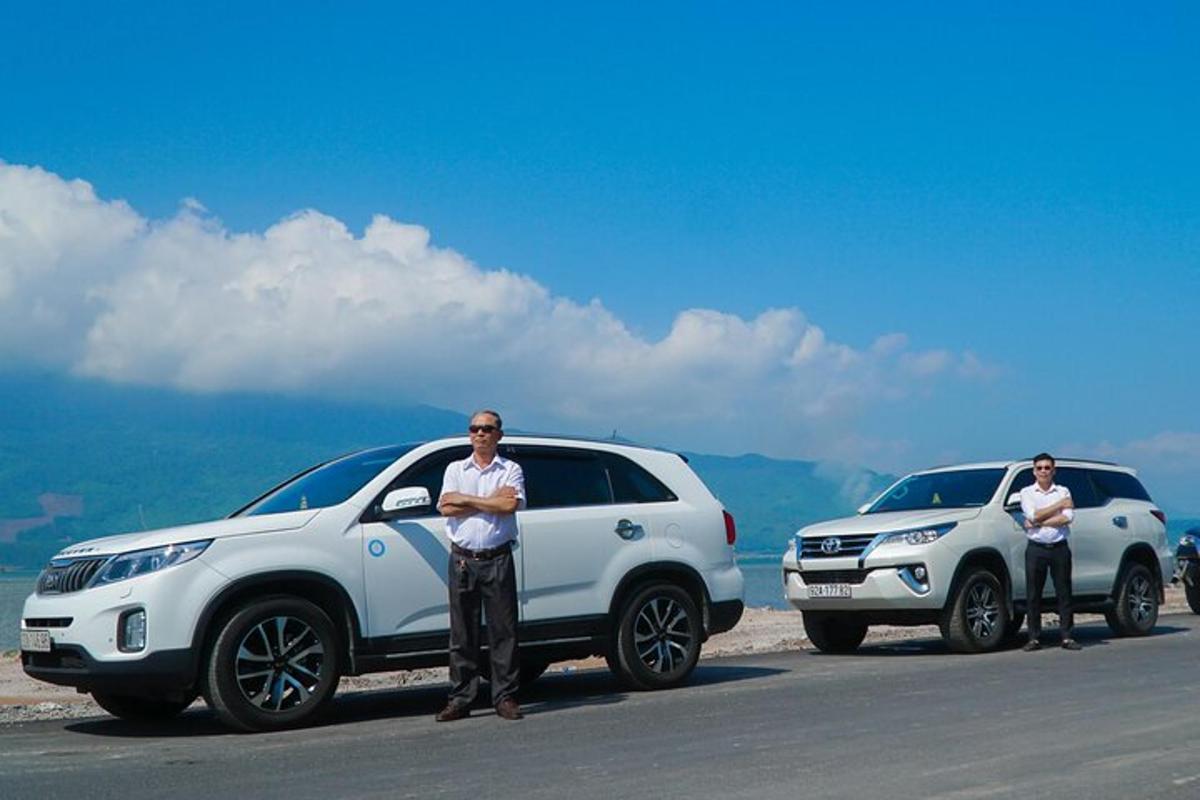 Dos hombres parados frente a dos coches blancos.