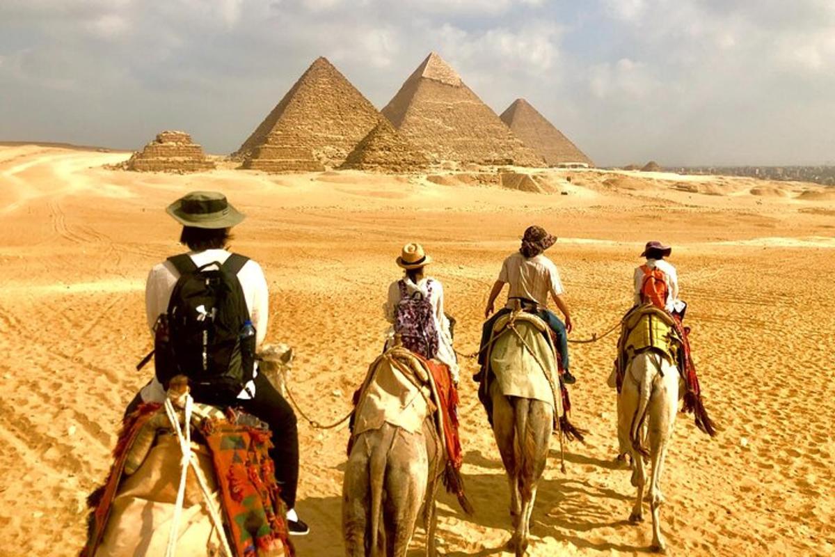 skupina ľudí jazdiacich na koňoch pred pyramídami