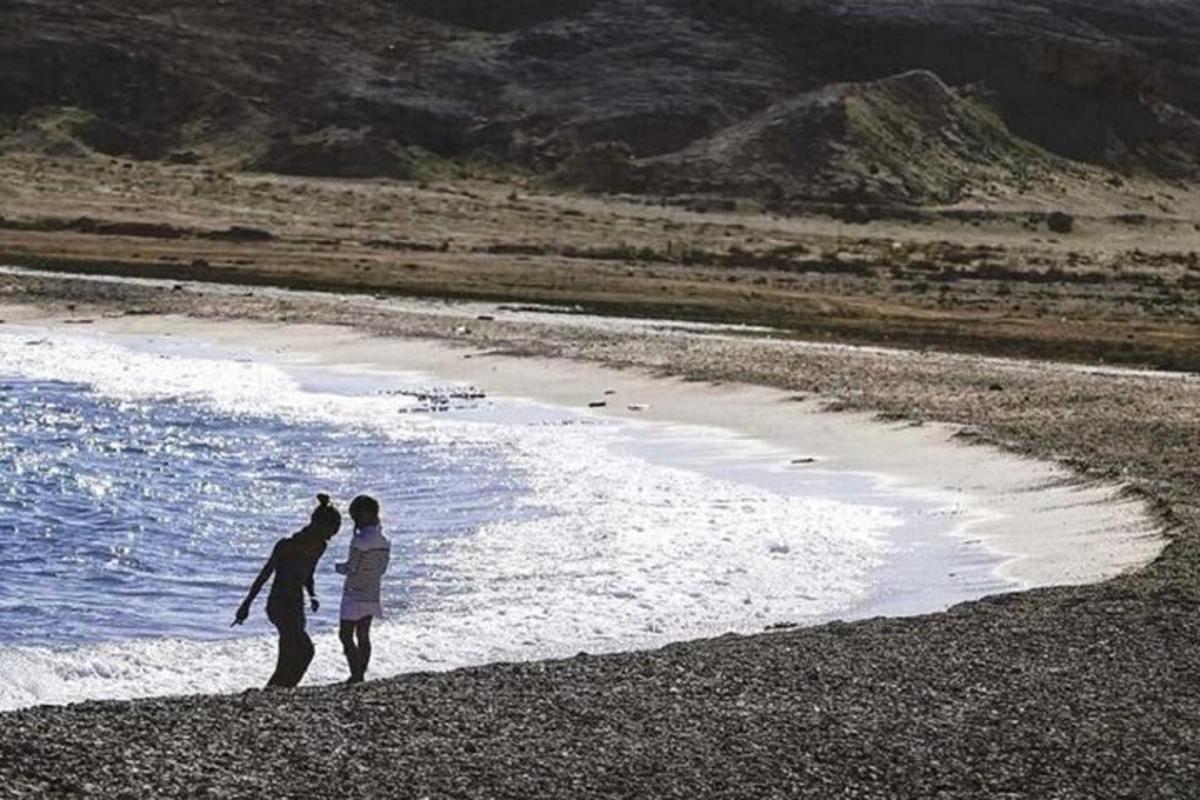 due persone in piedi su una spiaggia vicino all'acqua