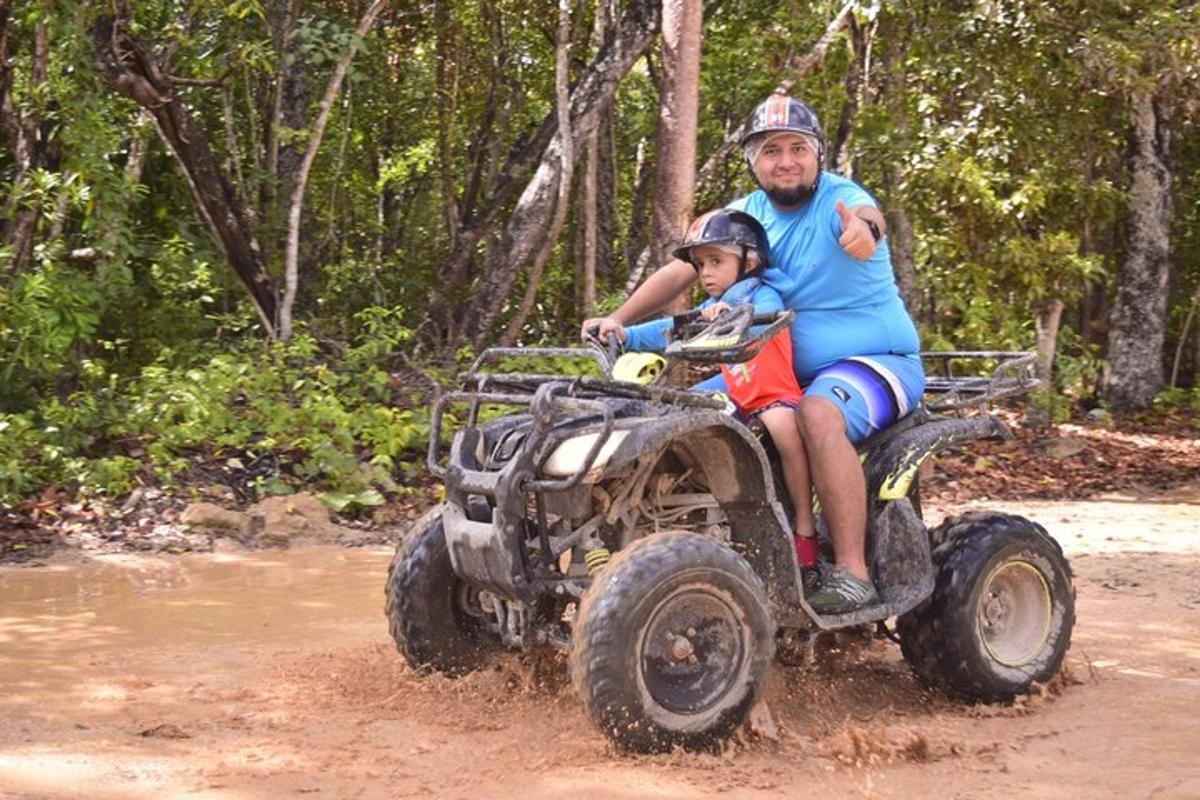 isang lalaki at isang bata na nakasakay sa isang four wheeler sa putikan