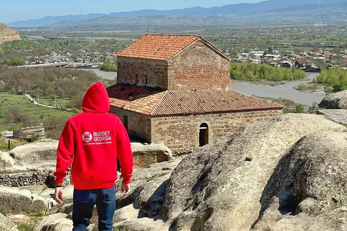 osoba v červenej mikine s kapucňou stojaca na streche budovy