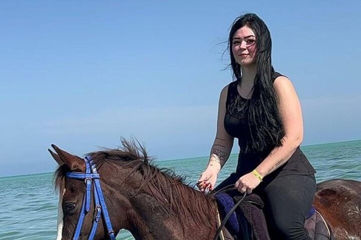 seorang wanita sedang menunggang kuda di laut