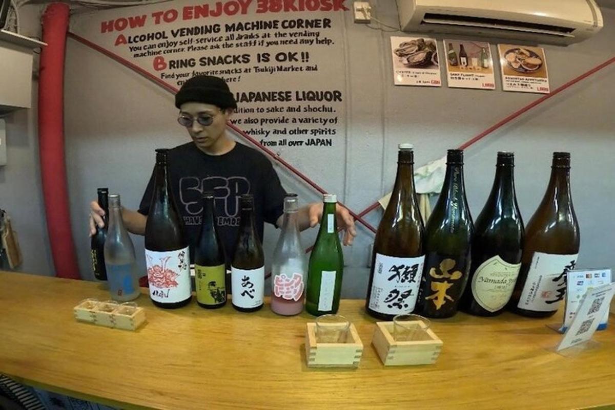 Un hombre de pie detrás de una mesa con botellas de vino.