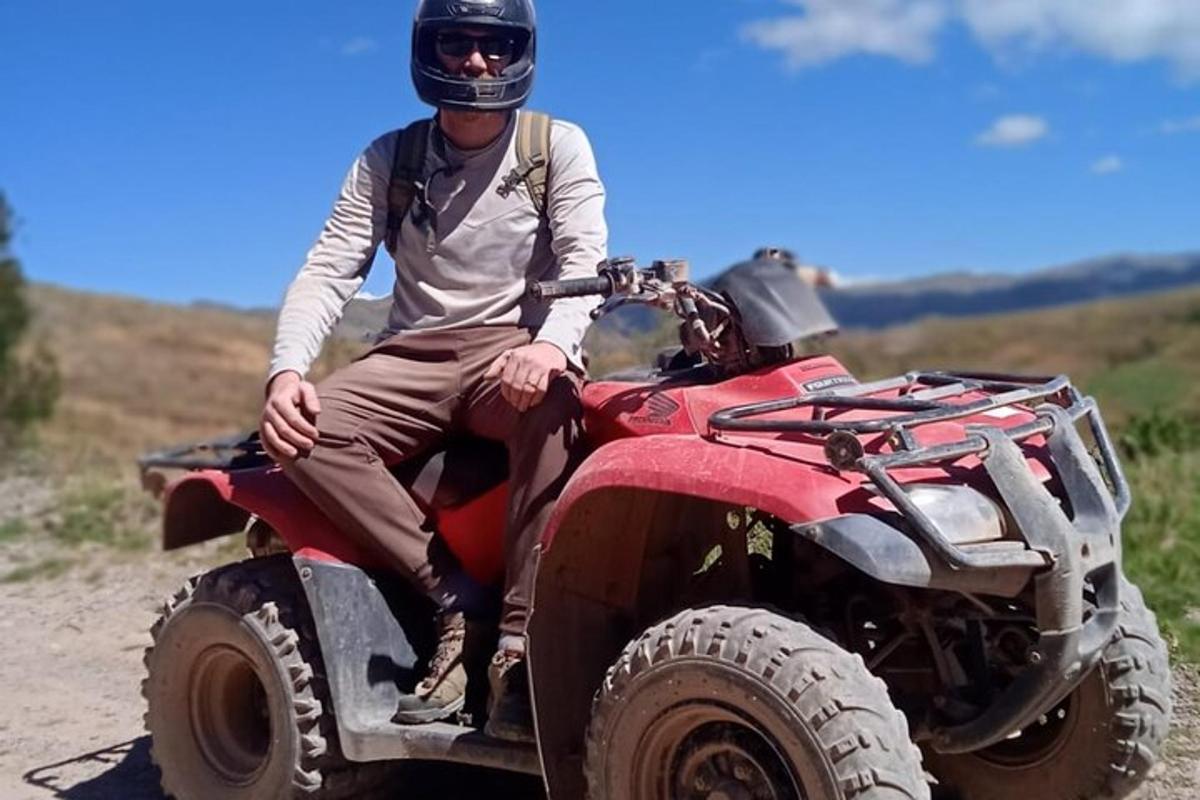 un homme à l'arrière d'un véhicule à quatre roues sur un chemin de terre