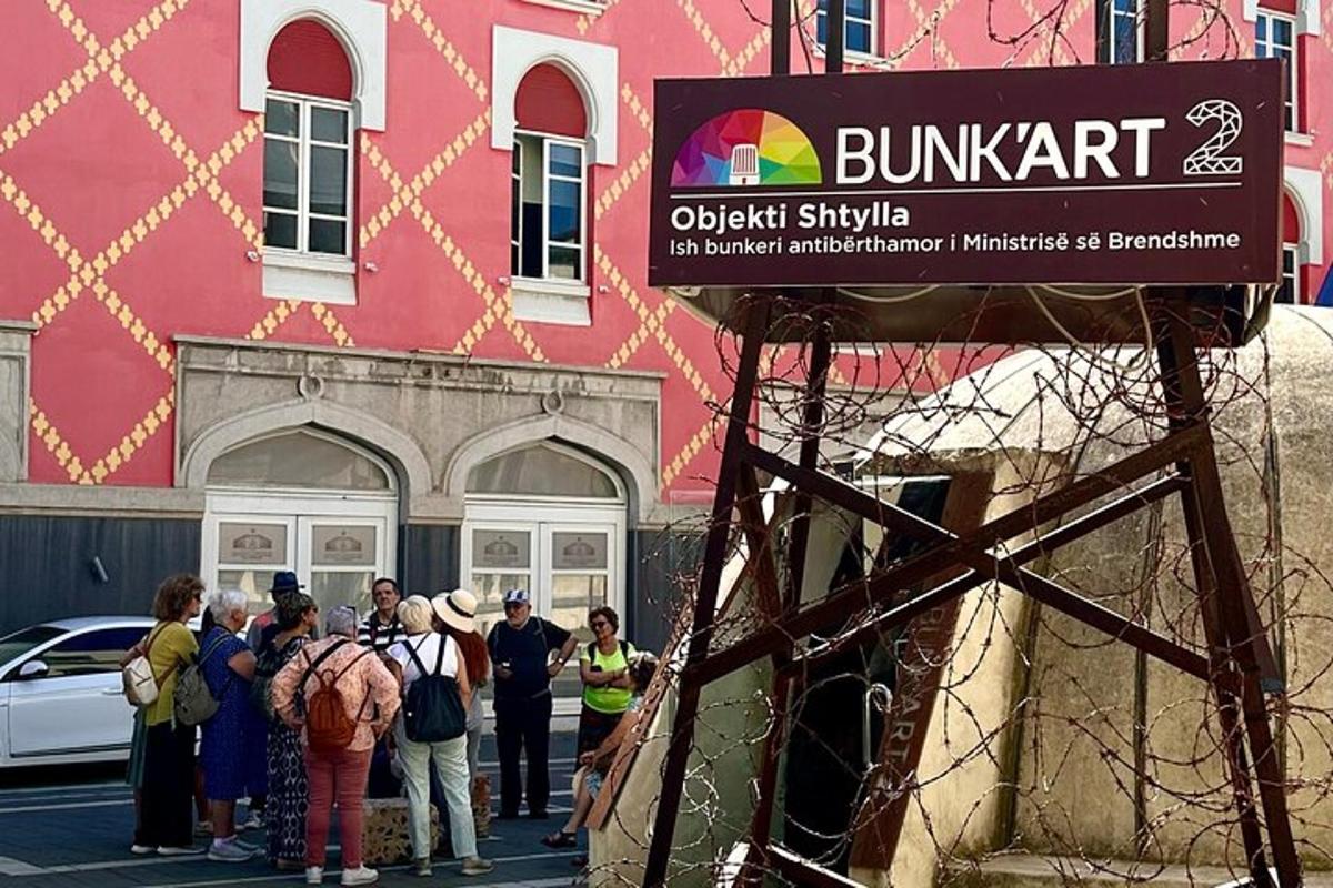 skupina lidí stojící před růžovou budovou