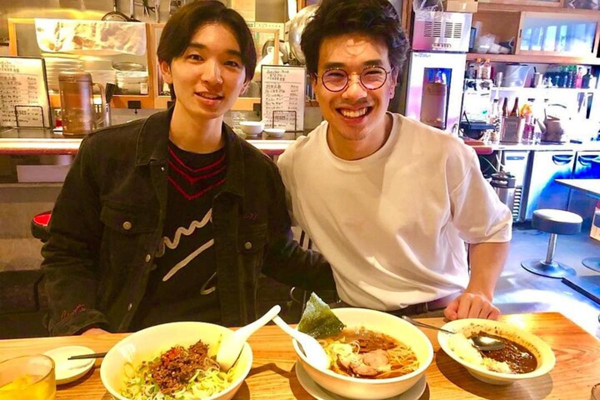 ผู้ชายสองคนกำลังนั่งอยู่ที่โต๊ะพร้อมจานอาหาร