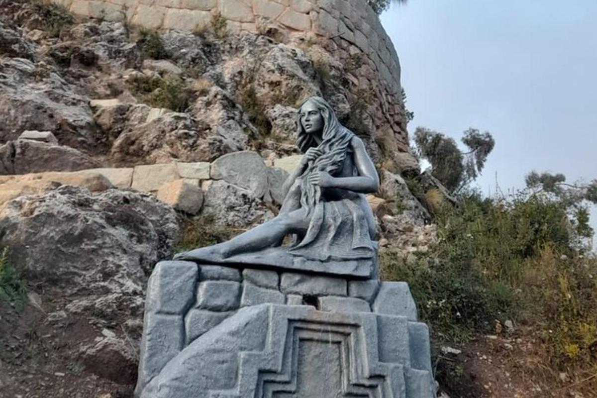 una estàtua d'una dona asseguda sobre una roca