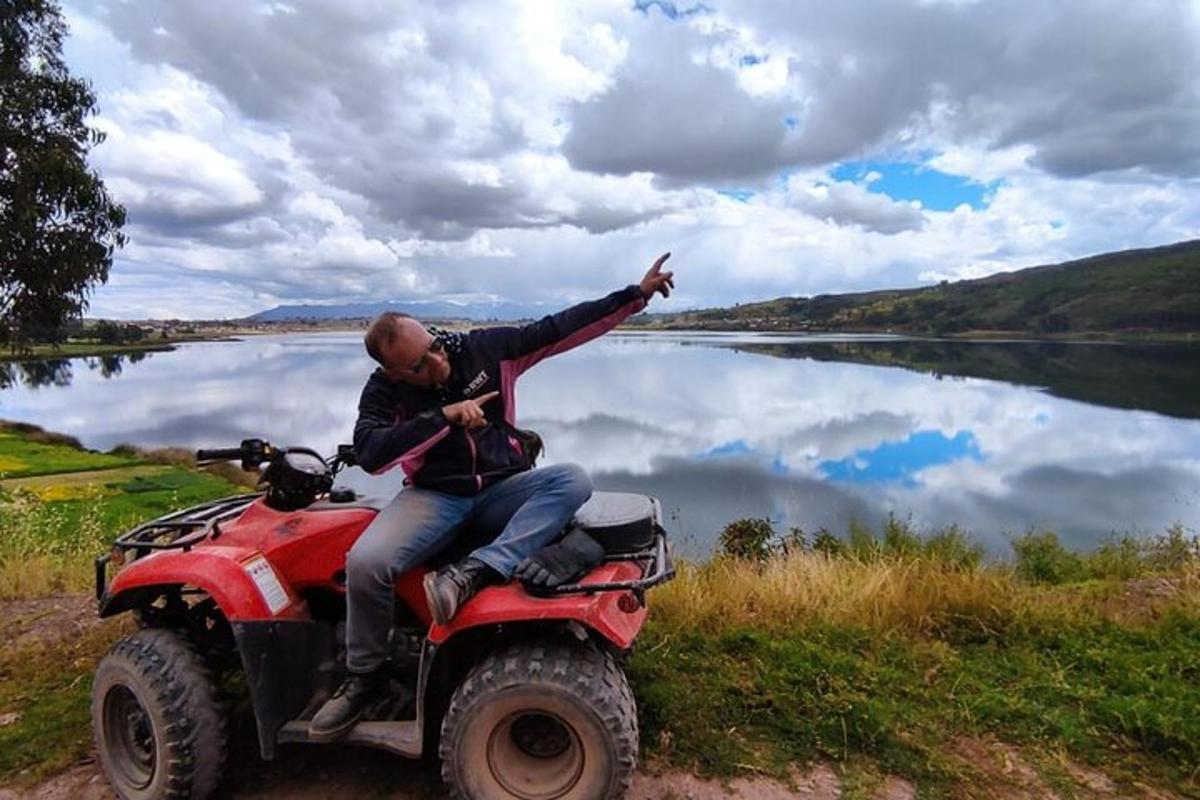 un home assegut en un quad al costat d'un llac