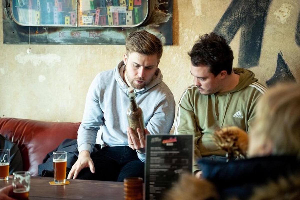 two men sitting at a table looking at a laptop