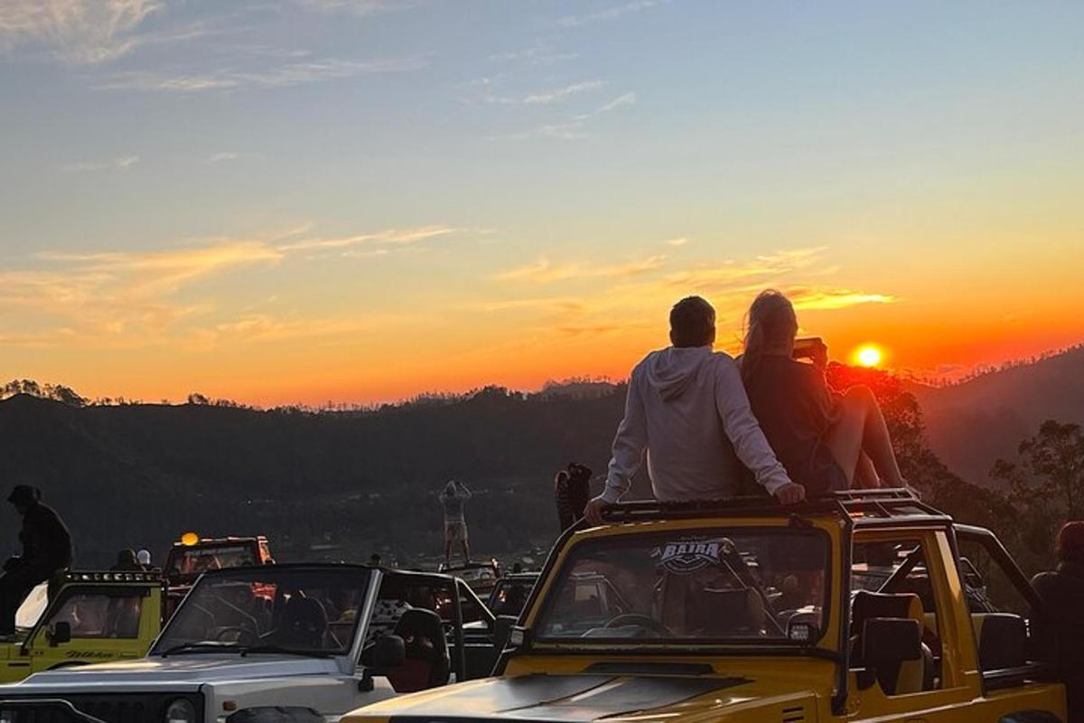 două persoane stând pe un jeep la apus