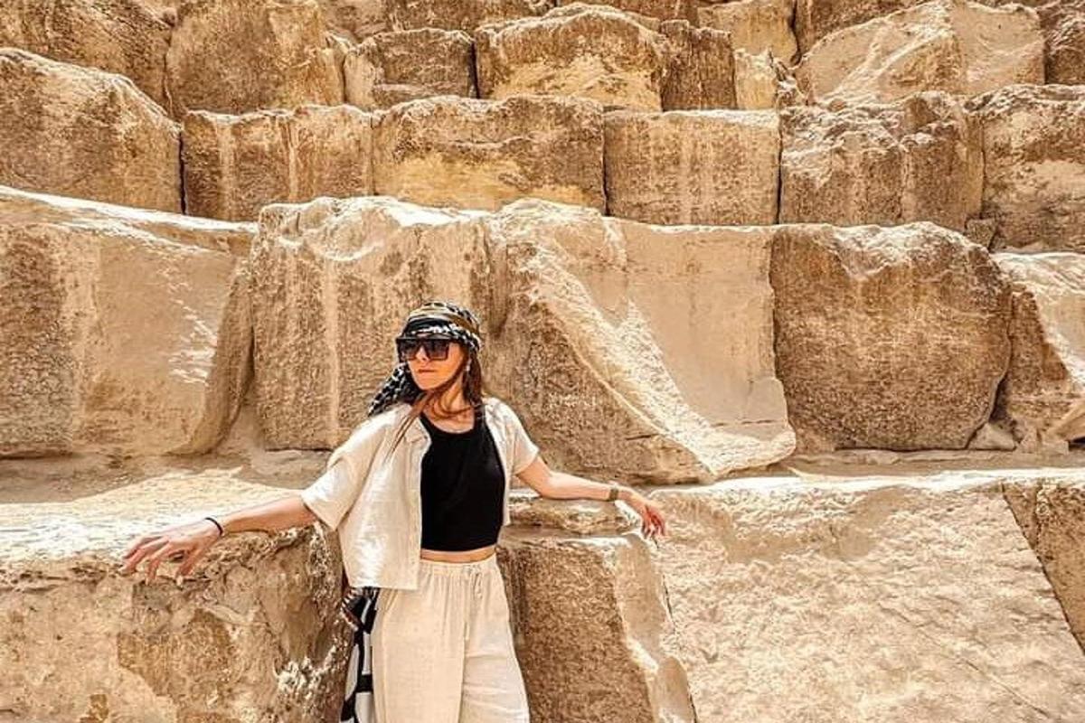 a woman is standing next to a rock wall