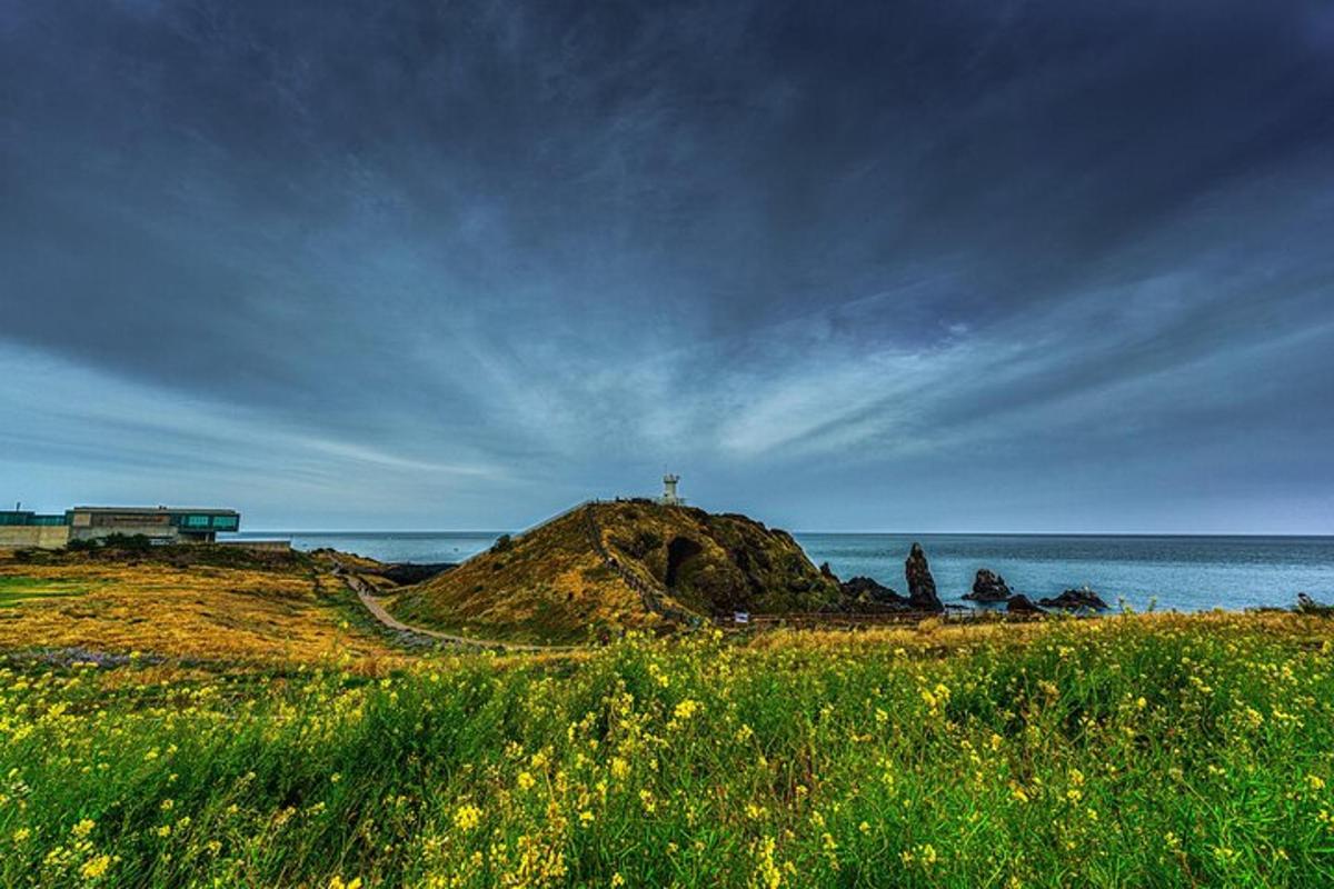 a hill with a cross on top of it next to the ocean