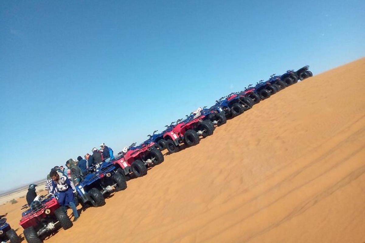 um grande grupo de pessoas andando de veículos em uma colina de areia