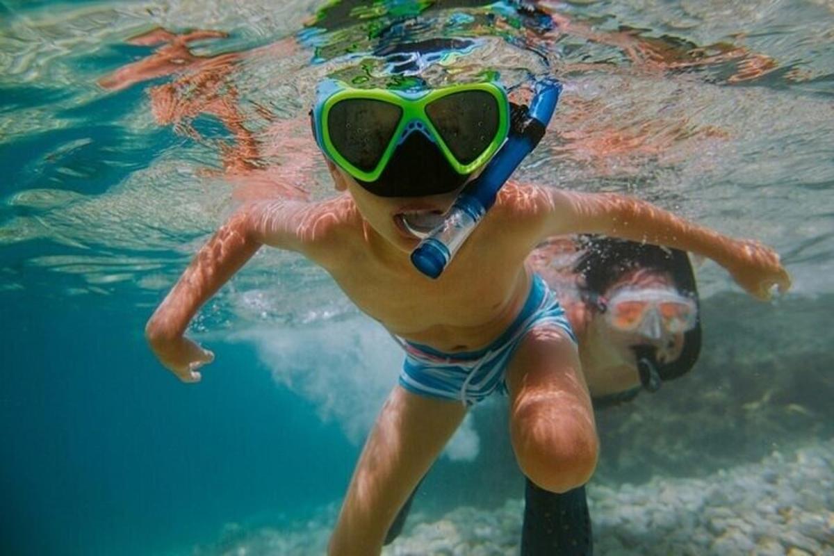 seorang anak laki-laki mengenakan kacamata dan berenang di air